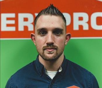Male employee with beard hair and dark blonde hair in front of SERVPRO logo background