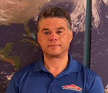Male employee with gray-black hair in front of a map background