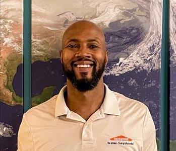 Male employee with beard hair smiling in front of a map background